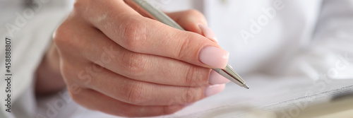 Woman doctor writes patient data into documents with pen