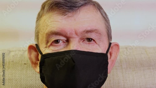 Old senior man puts on medical mask against viruses, close up. Elderly man applies protection against Coranavirus COVID-19. . High quality 4k footage photo