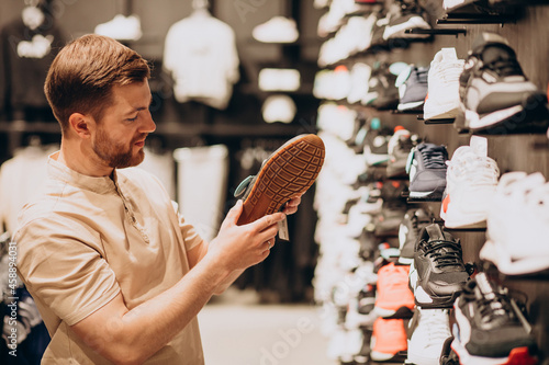 Schilderij op canvas Young man choosing sneakers at sportswear shop