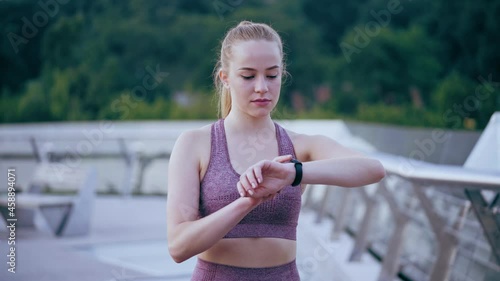 Young athletic woman timing her training and checking pulse and blood pressure photo