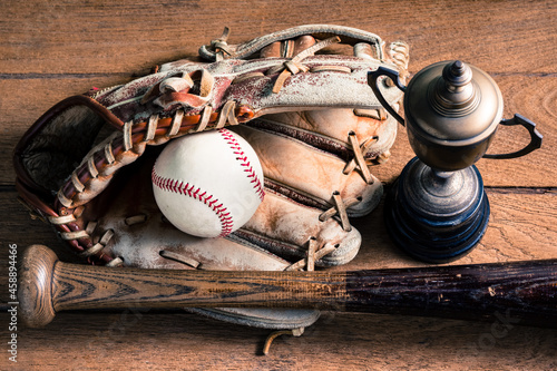 Photography worn out baseball equipment ( ball, baseball bat and glove ) with old trophy on