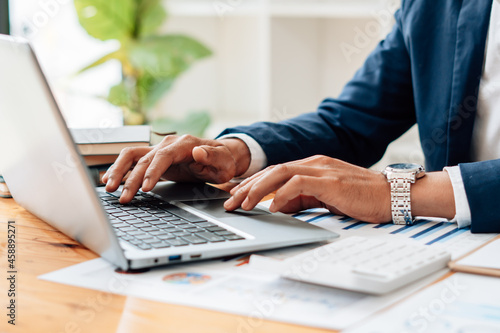 Close up of businessman or accountant working on laptop computer for calculate business data, accounting document and calculator at office, business concept