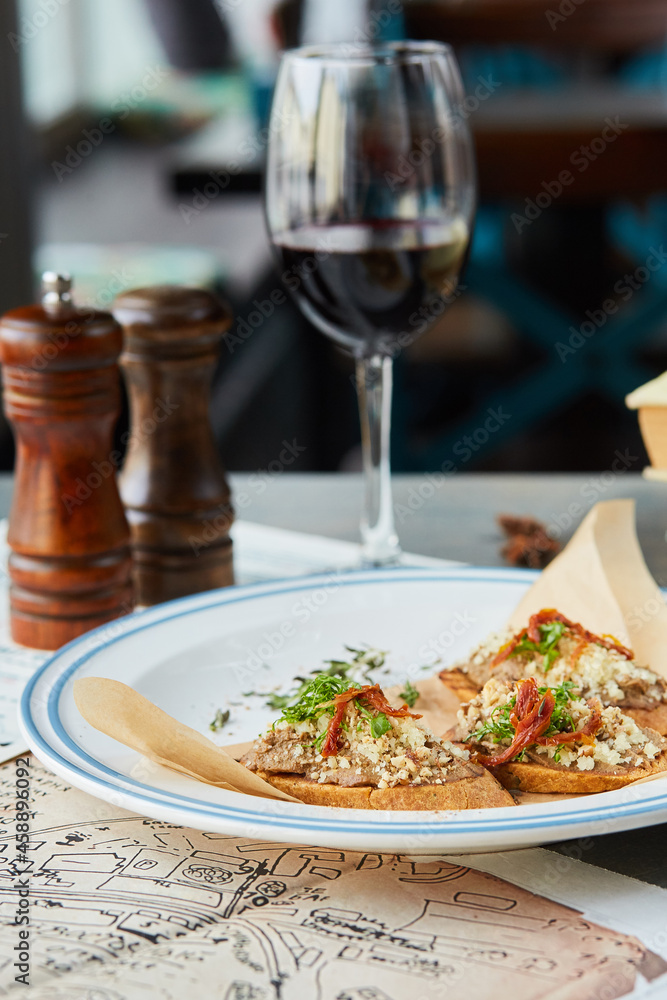 bruschetta on a wooden table in a white plate and a glass of wine