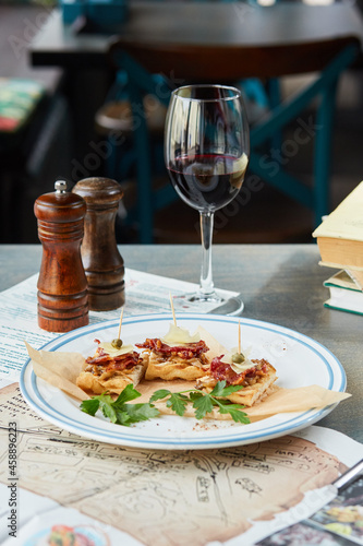 bruschetta on a wooden table in a white plate and a glass of red wine