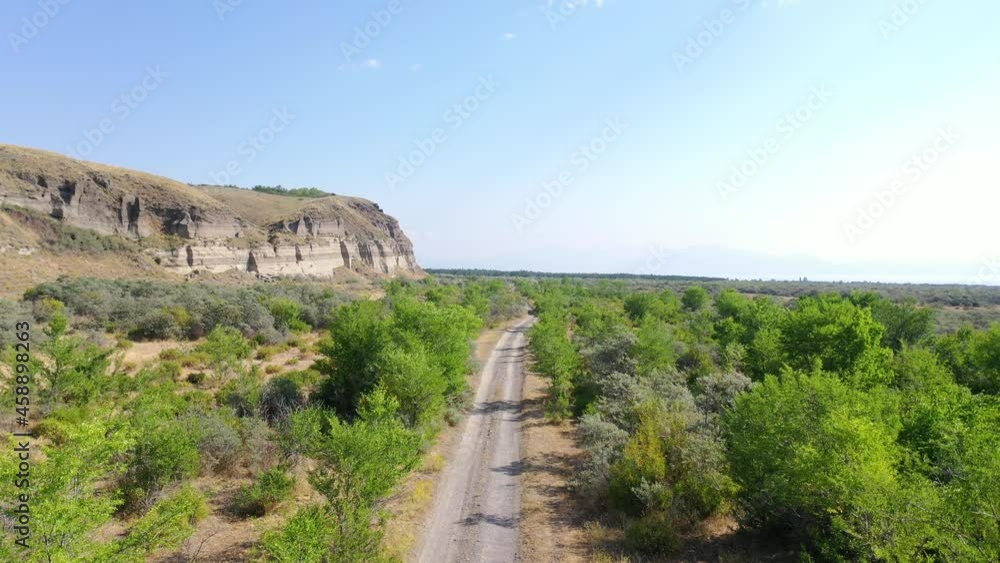 Aerial view road between trees. Off road near sand mine. Aerial footage road between field with dry grass and small trees. It's located near Sevan Lake, Armenia. Aerial view road between trees. Off road near sand mine. Aerial footage road between field with dry grass and small trees. It's located near Sevan Lake, Armenia.