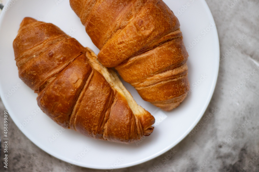 Fresh croissants on a white plate on a light background Fresh croissants on a white plate on a light background