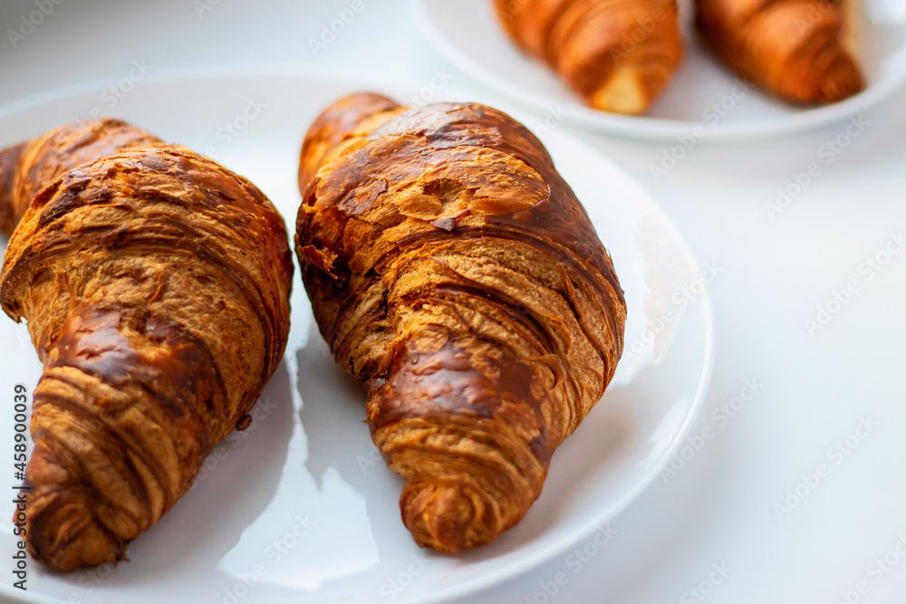 Fresh croissants on a white plate on a dark background