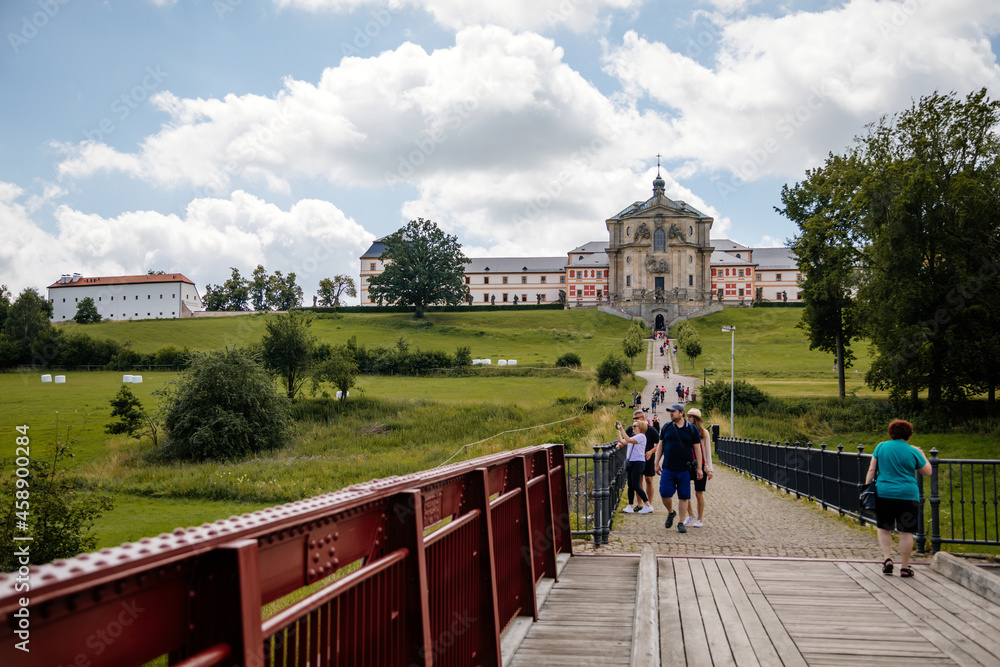 Kuks, East Bohemia, Czech Republic, 10 July 2021: State baroque castle and hospital Kuks with garden and Braun statues, Beautiful complex with chateau and Holy Trinity Church at sunny summer day.