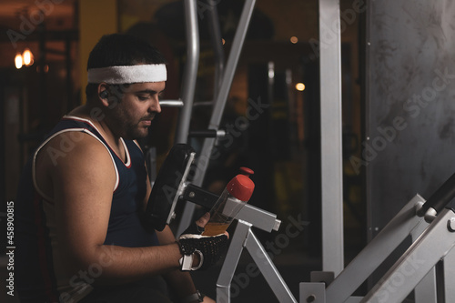 a funny fat boy doing sports inside a gym.
overcoming concept.
willpower. photo