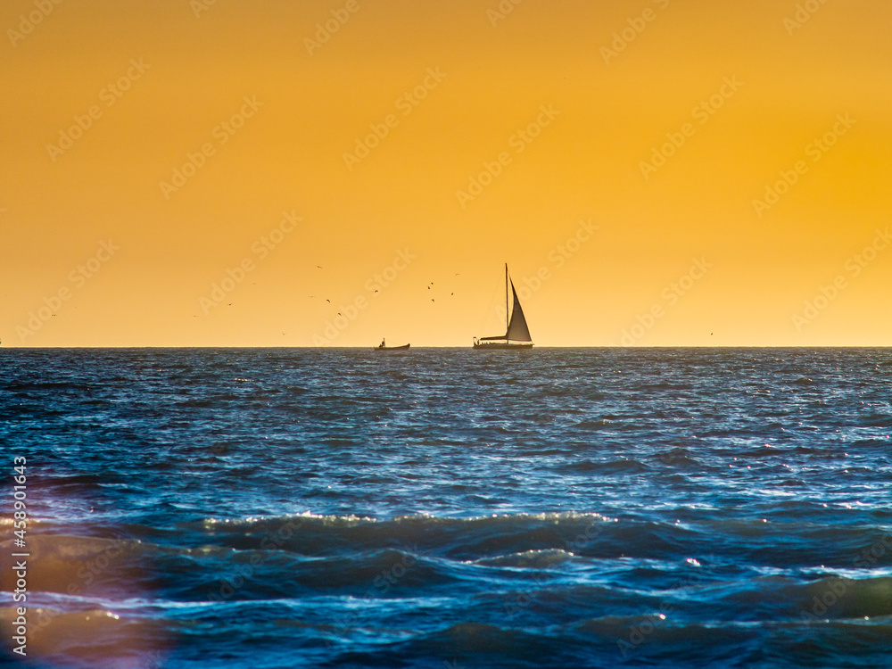 Sailboat on the horizon sailing at sunset