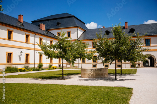 Fototapeta Naklejka Na Ścianę i Meble -  Kuks, East Bohemia, Czech Republic, 10 July 2021: Baroque castle and hospital Kuks, courtyard with garden and antique facade, Beautiful complex with chateau, Holy Trinity Church at sunny summer day.