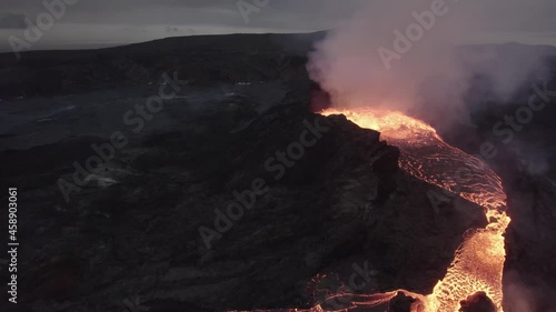 Aerial drone view towards a splattering magma crater, active Volcano surface photo