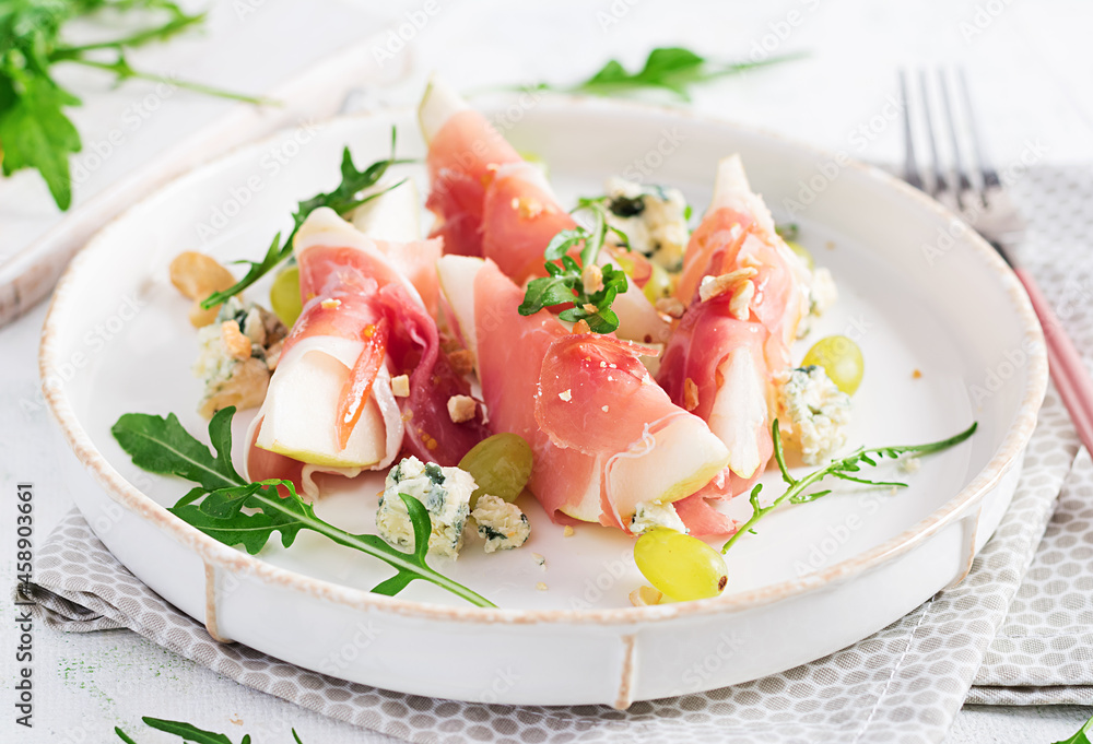 Appetizer with pear, blue cheese and prosciutto ham for holidays on a white plate. Appetizer with pear, blue cheese and prosciutto ham for holidays on a white plate.