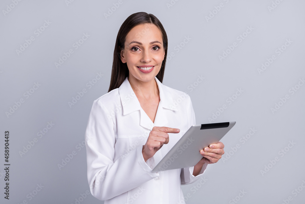 Portrait of attractive cheery nurse doctor using tablet medical science research isolated over grey pastel color background Portrait of attractive cheery nurse doctor using tablet medical science research isolated over grey pastel color background