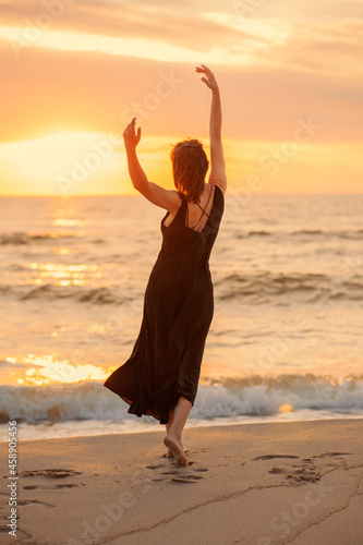 Beautiful woman dancing in dress near the sea at sunset