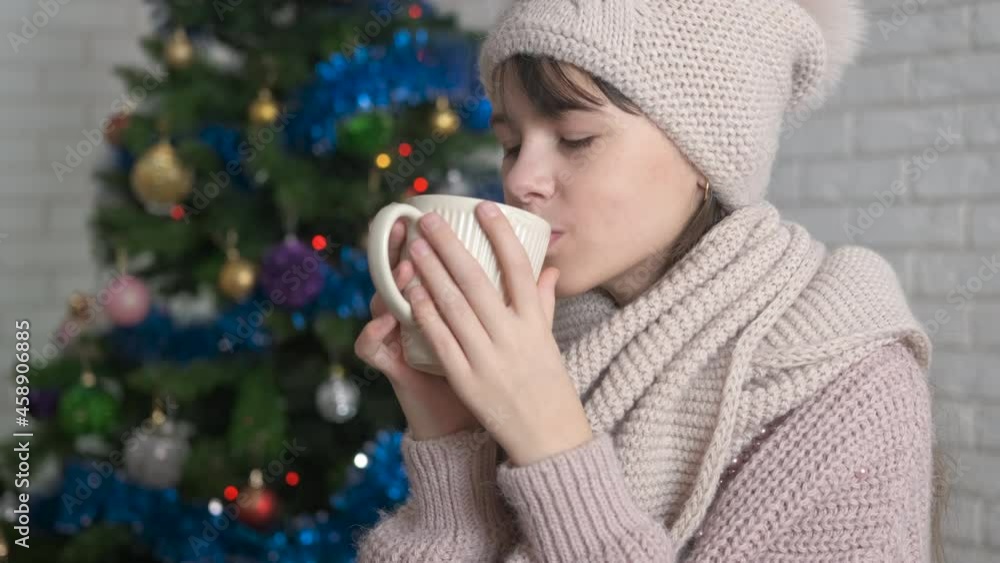 Christmas leisure with tea. A view of a happy child in woolen hat drink hot tea in the Christmas room. Christmas leisure with tea. A view of a happy child in woolen hat drink hot tea in the Christmas room.