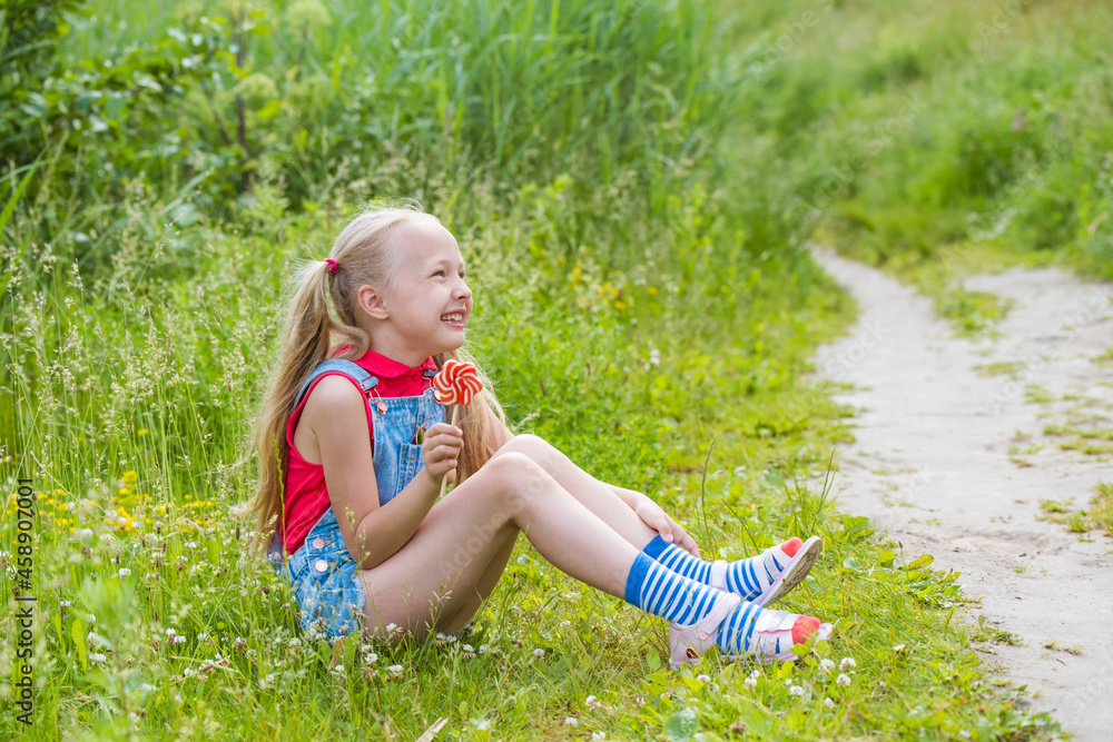 Blonde little girl with long hair and candy on a stick Blonde little girl with long hair and candy on a stick