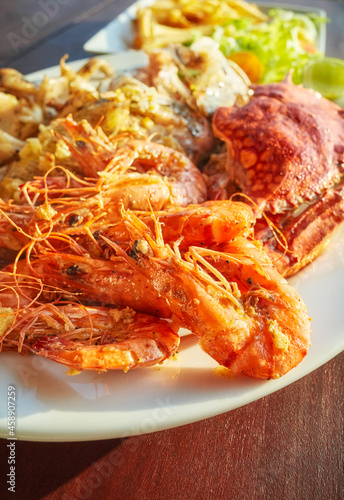 Grilled seafood platter with crab, fish and prawns in garlic sauce, selective focus.
