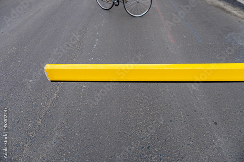 A bike is riding on the street and a yelloew fence crossed the street photo