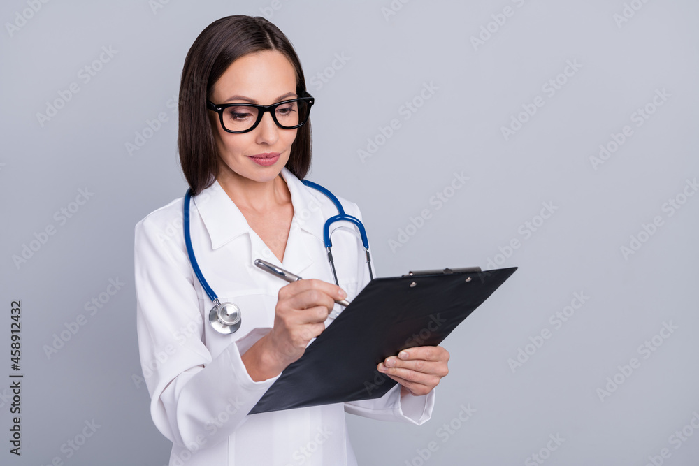 Photo of mature woman write pen notes clipboard doctor diagnostics patient medicine isolated over grey color background Photo of mature woman write pen notes clipboard doctor diagnostics patient medicine isolated over grey color background