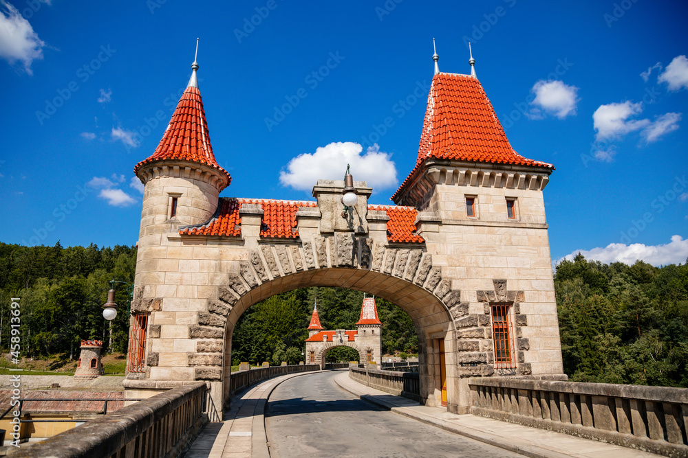 Bila Tremesna, Czech Republic, 10 July 2021: Amazing colorful view of Les Kralovstvi historic hydraulic water dam with orange water in river Elbe, Kingdom Forest, road with towers at sunny summer day