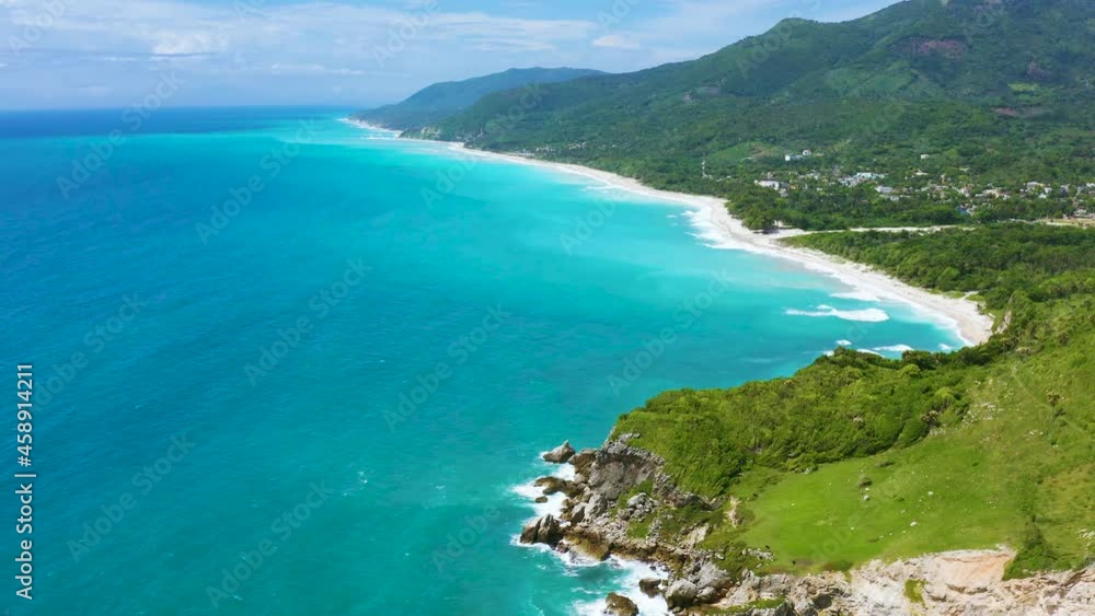 Glowing turquoise ocean with a white strip of sandy wild beach. A green peninsula covered with dense thickets of tropical flora. Magnificent tropical mountain landscape. Glowing turquoise ocean with a white strip of sandy wild beach. A green peninsula covered with dense thickets of tropical flora. Magnificent tropical mountain landscape.