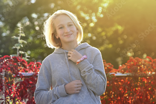 Happy blonde teen girl on a walk in the park. Autumn, sunny evening.