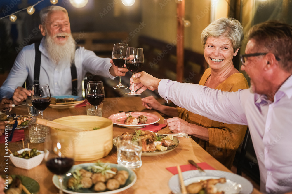 Senior people having fun cheering with wine at patio dinner - Focus on female face Senior people having fun cheering with wine at patio dinner - Focus on female face