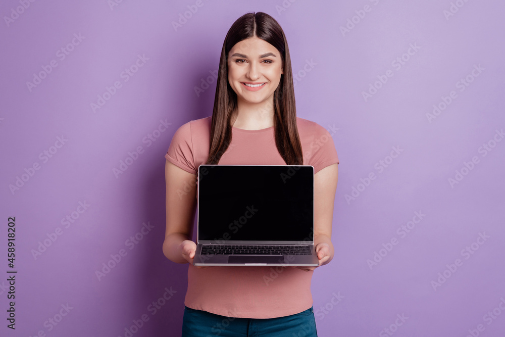 Portrait of friendly girl happy positive smile hands holding laptop showing display isolated on violet color background Portrait of friendly girl happy positive smile hands holding laptop showing display isolated on violet color background