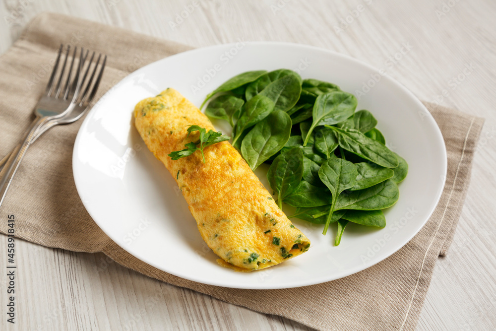 Homemade French Omelette with Fresh Herbs and Greens on a plate, low angle view.