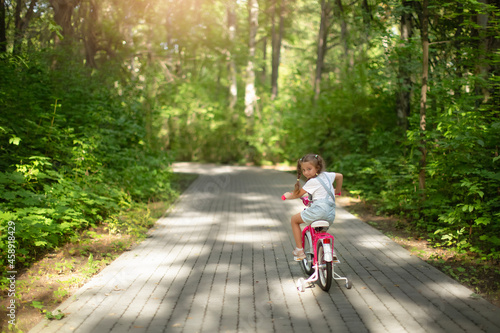 Wallpaper Mural happy cheerful child girl riding a bike in Park in the nature Torontodigital.ca