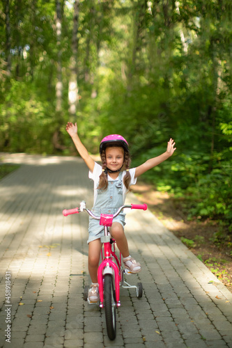 Fototapeta Naklejka Na Ścianę i Meble -  happy cheerful child girl riding a bike in Park in the nature