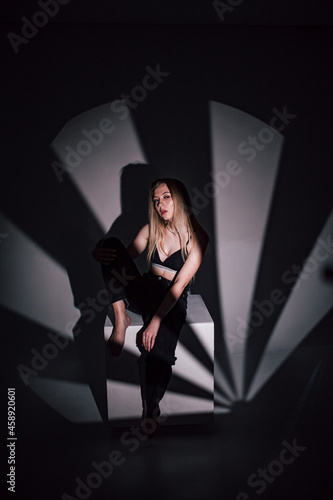 Leinwand Poster beautiful girl in a black bodice in the studio, chiaroscuro on her face