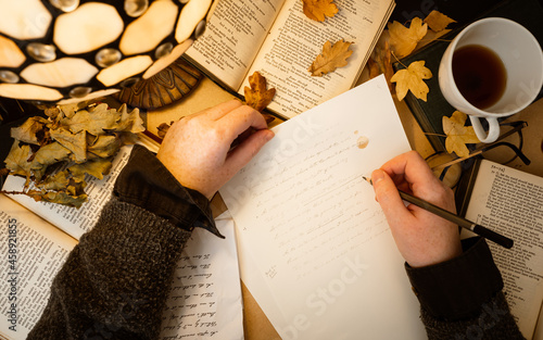 Dark academia aesthetic student studies Shakespeare sonnets surrounded by fallen autumn leaves 
