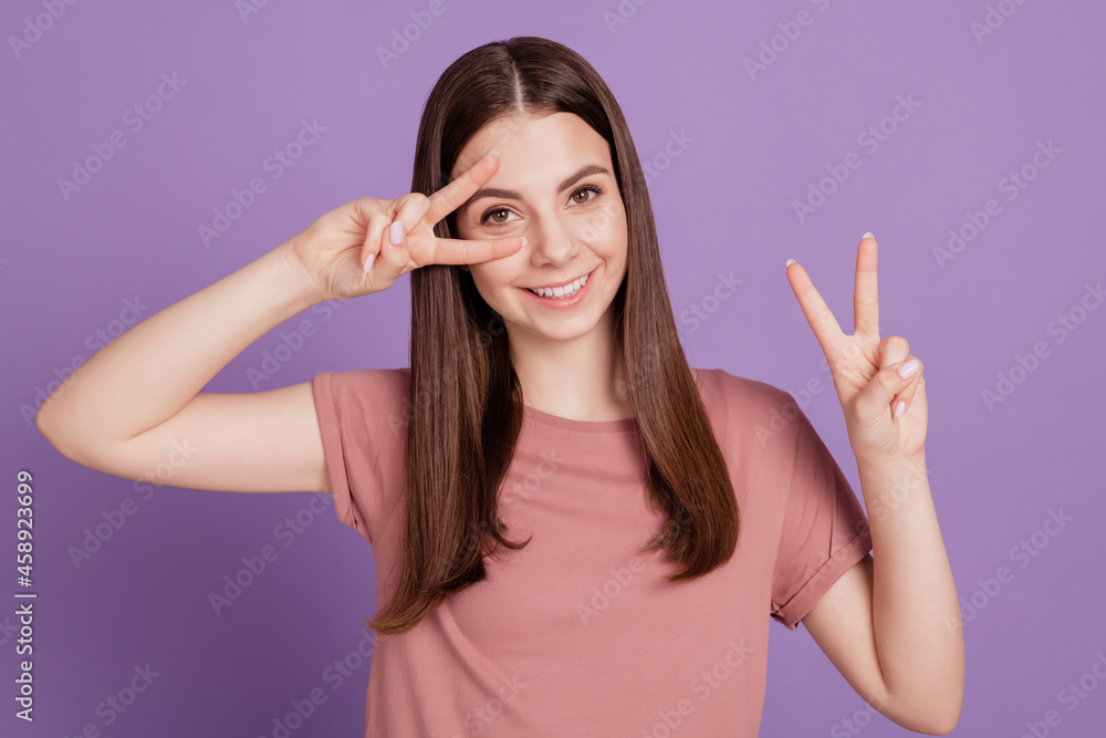 Portrait of positive girl gesturing two v-signs near face isolated on violet background Portrait of positive girl gesturing two v-signs near face isolated on violet background