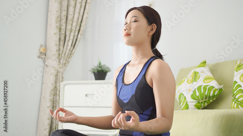 asian woman practicing yoga with focus at home