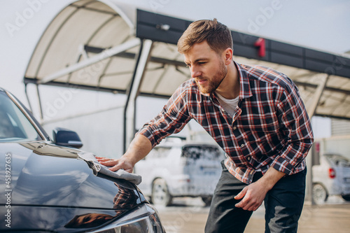 Young man wiping his car after car wash