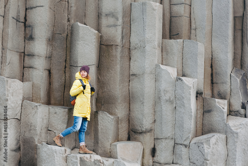Female traveler walking on rocky formations at Reynisfjara Beach, Vik, Iceland
