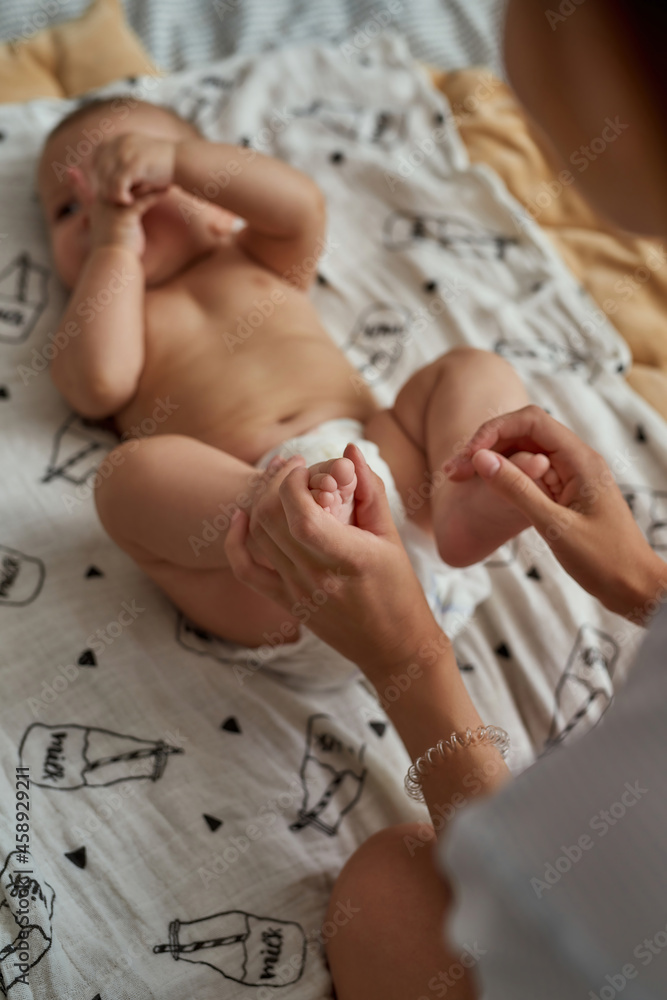Naklejka premium Supportive mother massaging relaxed baby feet, top view