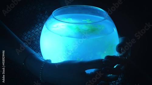 A girl holds a glowing aquarium