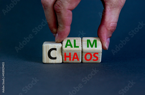 Stop chaos, time to calm. The words 'chaos' and 'calm' on wooden cubes. Beautiful grey background, copy space. Businessman hand. Business and chaos or calm concept.