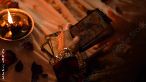 Mystical witch shuffles tarot cards in a dark room by candlelight. Mystic rites and traditions.