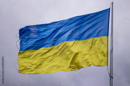Yellow and blue flag of Ukraine on the flagpole during a strong wind