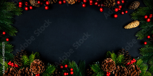 Christmas frame with holiday garland on black background. Top view. Traditional new year eve festive design with fir tree and pine cone from above. Celebration party invitation layout banner. photo