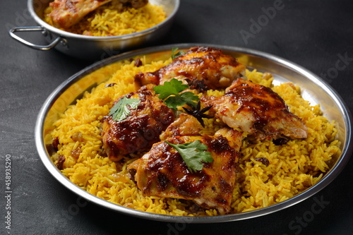 The national Saudi Arabian dish chicken kabsa with roasted chicken quarter and almonds, raisins, garlic and biryani rice photo