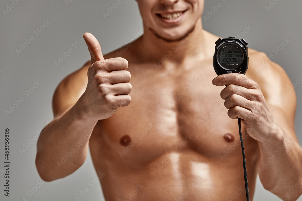 Fototapeta premium A coach with a stopwatch in his hands, a sports swimming coach with a timer in his hands, gray background, copy space.