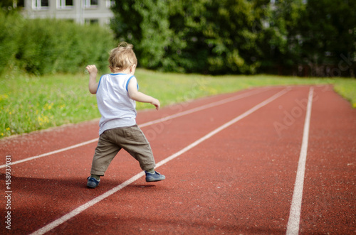 person running on the track, one year baby walking on the running track in the school playground