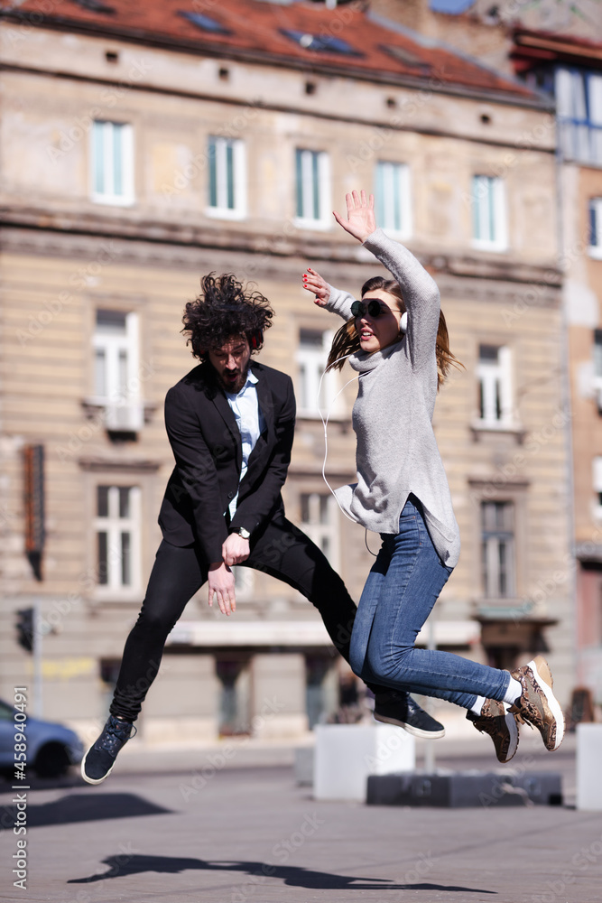 Young business colleagues dancing together with headphones after work. Happy friends jumping and fooling around outdoors Young business colleagues dancing together with headphones after work. Happy friends jumping and fooling around outdoors