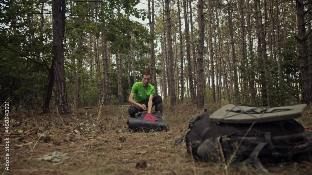 Survivalist in the forest sets up a tent. Gloomy Forest Survivalist in the forest sets up a tent. Gloomy Forest