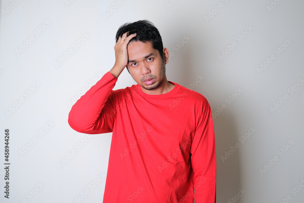 Asian man wearing red clothes looking stressed expression Asian man wearing red clothes looking stressed expression